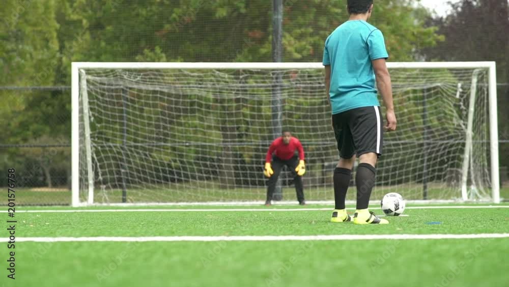 Male adult goalkeeper saves goal.