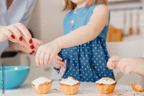 Photography Children with their hands sprinkle cupcakes with colored caramel for Easter