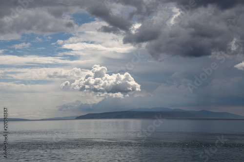 Seascape with beautiful clouds on croatian Adria and island silhouette on the horizon