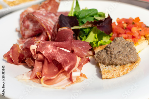 lorence, Tuscany/Italy - April 21, 2018. traditional Italian appetizers "antipasti": salami, dried meat (prosciutto), toast with tomatoes and olive oil (crostini), toast with pate, lettuce.