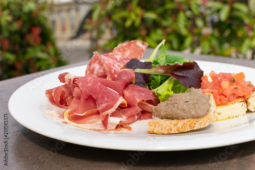 lorence, Tuscany/Italy - April 21, 2018. traditional Italian appetizers "antipasti": salami, dried meat (prosciutto), toast with tomatoes and olive oil (crostini), toast with pate, lettuce.