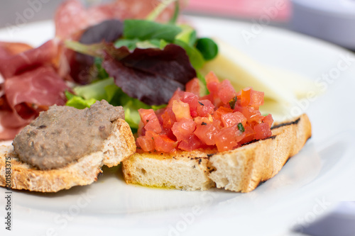 Florence, Tuscany/Italy - April 21, 2018. traditional Italian appetizers "antipasti": toast with tomatoes and olive oil (crostini), toast with pate, lettuce.