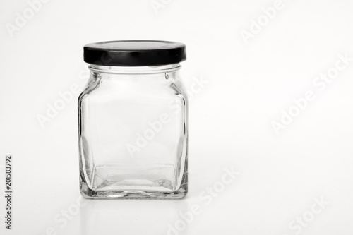 Square empty glass jar with black lid.