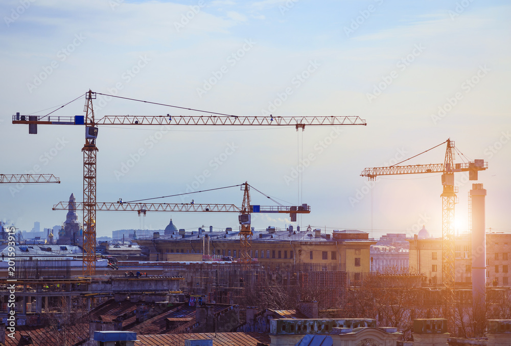 construction cranes over the city in the evening construction cranes over the city in the evening