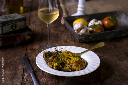Plato de paella con vino en mesa rústica
