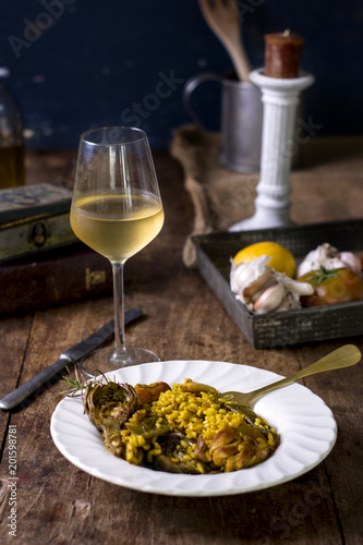 Plato de paella con vino en una mesa de madera