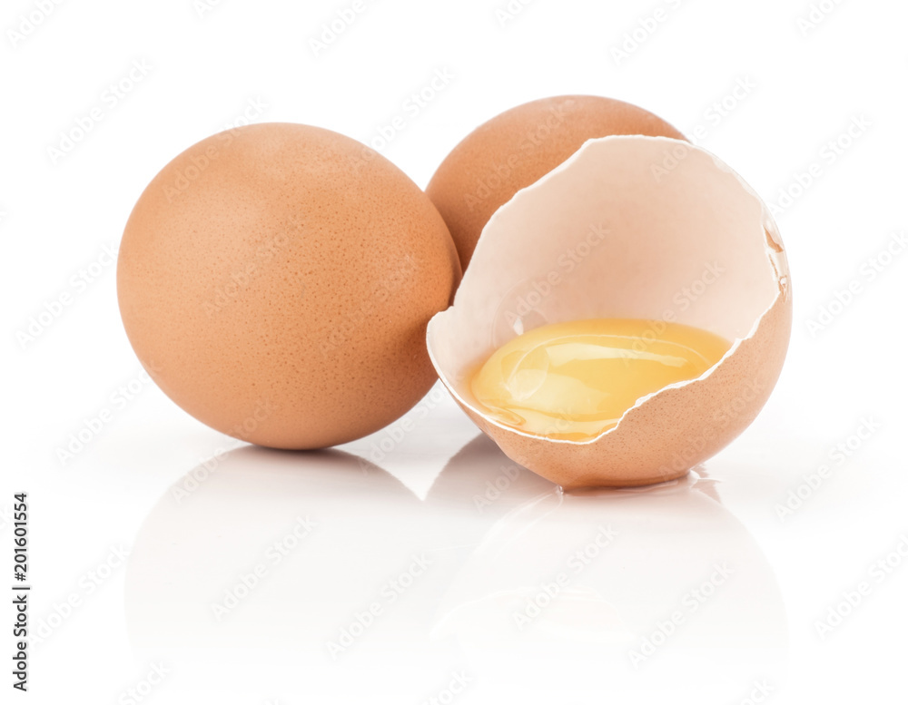 Two brown chicken eggs with one raw yolk in the eggshell half isolated on white background. Two brown chicken eggs with one raw yolk in the eggshell half isolated on white background.