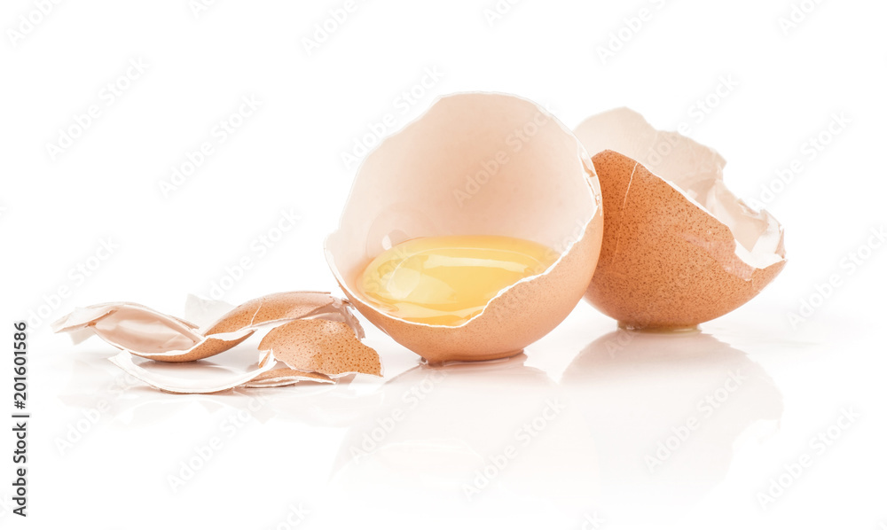 One raw yolk in a brown chicken eggshell two halves with a lot of cracked pieces isolated on white background. One raw yolk in a brown chicken eggshell two halves with a lot of cracked pieces isolated on white background.