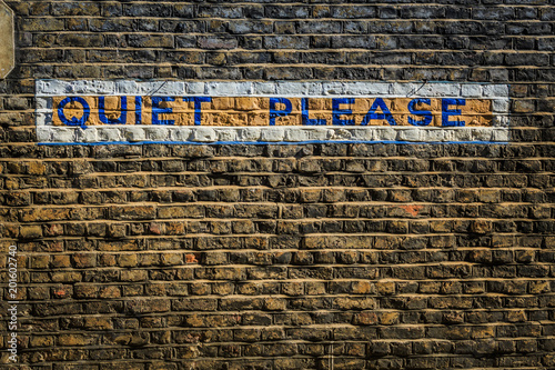 Foto Words Quiet Please painted on a grungy brick wall in block type taken in London