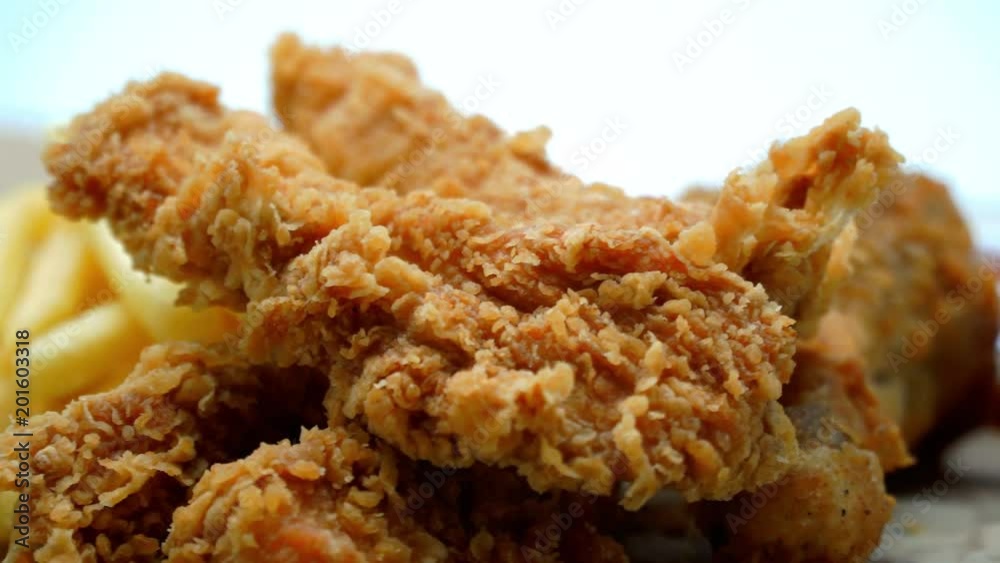 Crispy fried chicken wings and legs with french fries on a wooden table rotation. Breaded Crispy chicken, fried potato tasty dinner. 4K Crispy fried chicken wings and legs with french fries on a wooden table rotation. Breaded Crispy chicken, fried potato tasty dinner. 4K