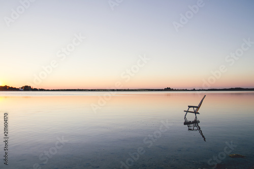 Empty chair in the water of a blue lake