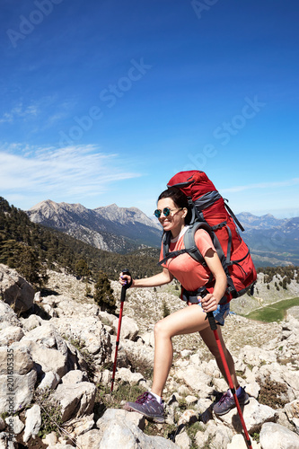 Summer hike in the mountains with a backpack and tent along the path to the top.