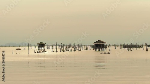 Gold sky reflect surface of calm water in lake at sunset with silhouette houseboat and floating basket.