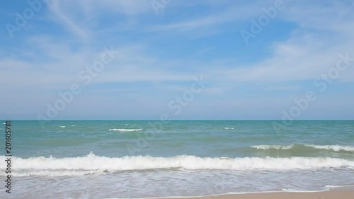 Beautiful white clouds and sea waves on the tropical beach on a cloudy day with blue sky.