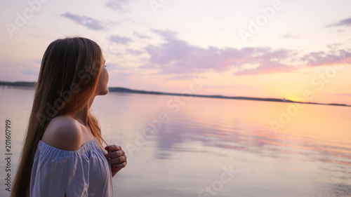Young girl on the background of the sea and sunset.