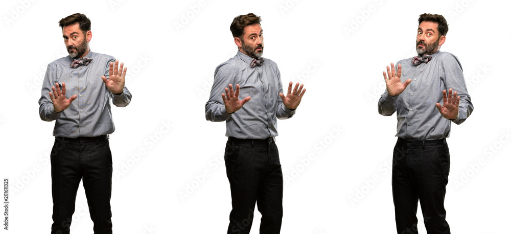 Middle age man, with beard and bow tie annoyed with bad attitude making stop sign with hand, saying no, expressing security, defense or restriction, maybe pushing Middle age man, with beard and bow tie annoyed with bad attitude making stop sign with hand, saying no, expressing security, defense or restriction, maybe pushing