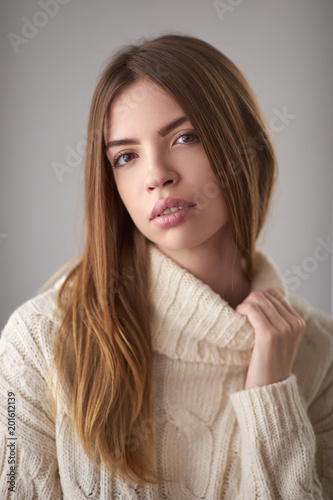 Concept: professional fashion lifestyle. Beautiful model posing in studio during classic test shooting wearing white sweater. Woman show poses and emotions. Portrait calm and serious
