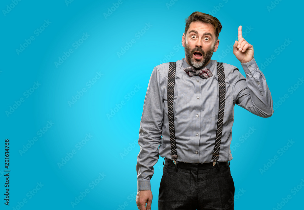 Middle age man, with beard and bow tie happy and surprised cheering expressing wow gesture pointing up Middle age man, with beard and bow tie happy and surprised cheering expressing wow gesture pointing up