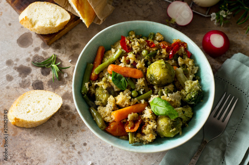Healthy proper nutrition. Dietary vegan dish: couscous and vegetables (string beans, brussels sprouts, carrots, sweet peppers, tomatoes) on a stone or slate background.