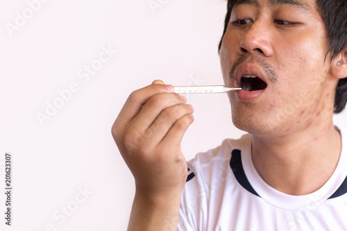 Sick man with thermometer in mouth,looking and worry at thermometer on white background,healthcare concept
