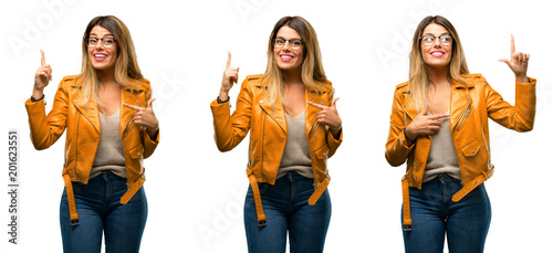 Beautiful young woman happy and surprised cheering expressing wow gesture pointing up over white background