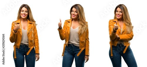 Beautiful young woman smiling broadly showing thumbs up gesture to camera  expression of like and approval over white background