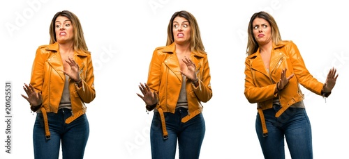 Beautiful young woman disgusted and angry, keeping hands in stop gesture, as a defense, shouting over white background