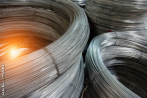 The blurry light design background of galvanize wire roll stacked ,in factory ,prepare for produce,warm light tone.