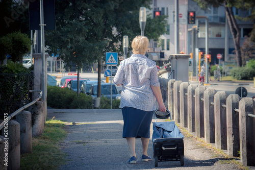 old woman with trolley, mature female walking in the city

