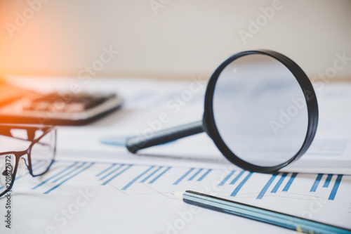 charts and graphs with magnifying glass and pencil, calculator. Reflection light and flare. Concept image of data gathering and statistical working. photo