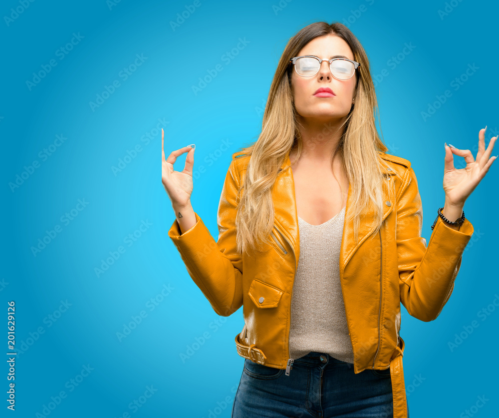 Beautiful young woman doing ok sign gesture with both hands expressing meditation and relaxation, blue background