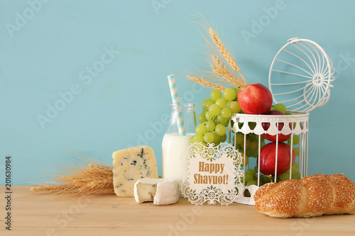 image of fruits, bread and cheese in decorative basket over wooden table.