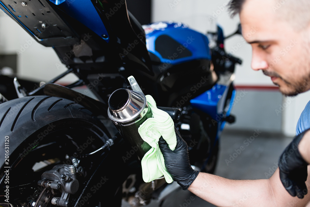 Fototapeta premium A man cleaning motorcycle with cloth. Selective focus. 