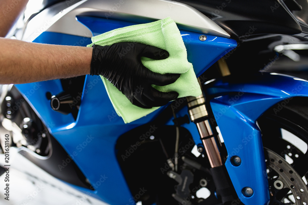 Naklejka premium Mężczyzna czyści motocykl szmatką. Selektywna ostrość.