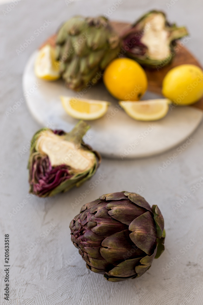 Obraz premium Healthy lifestyle concept. Artichokes and lemons on concrete tab
