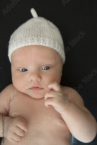 Portrait of cute newborn child in a white hat on a black background
