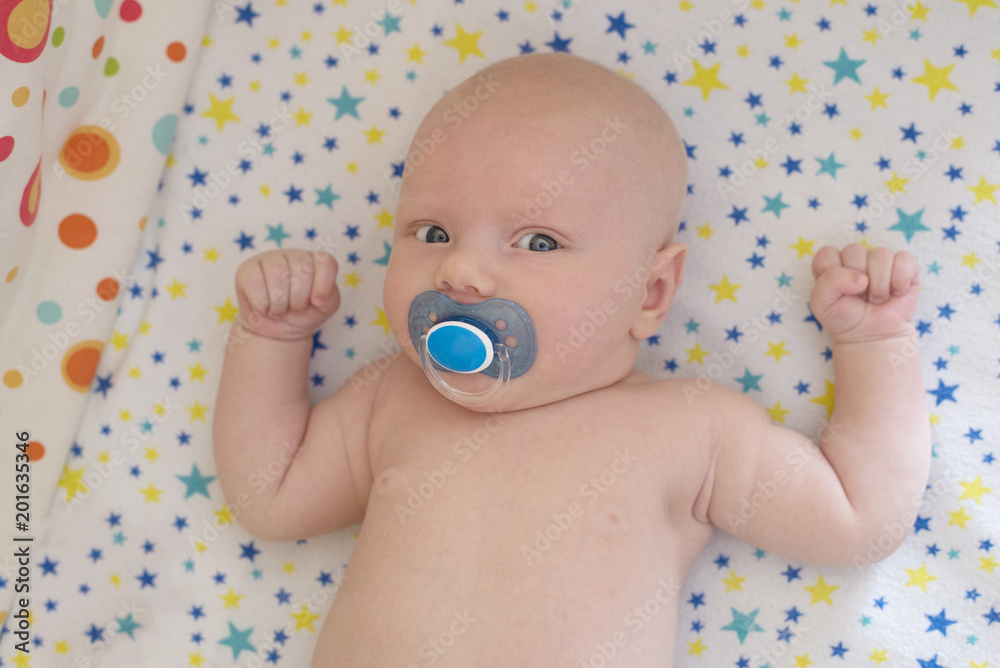 A newborn baby lies in crib and sucks a pacifier A newborn baby lies in crib and sucks a pacifier