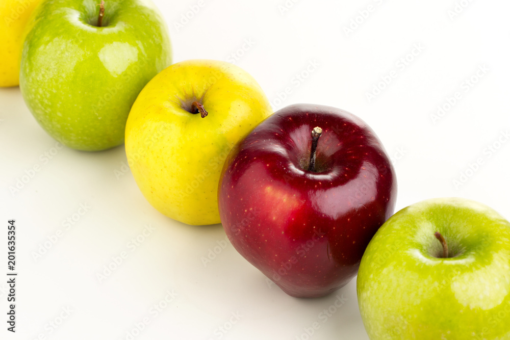 Multicolored apples in a row on a white table Multicolored apples in a row on a white table