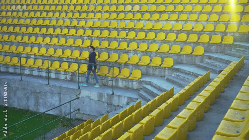 custom made wallpaper toronto digitalThe girl in the blue windbreaker is leaving the podium of the stadium. Canceled match, game. An empty stadium without fans. Spectators are not allowed into the stadium. 4k