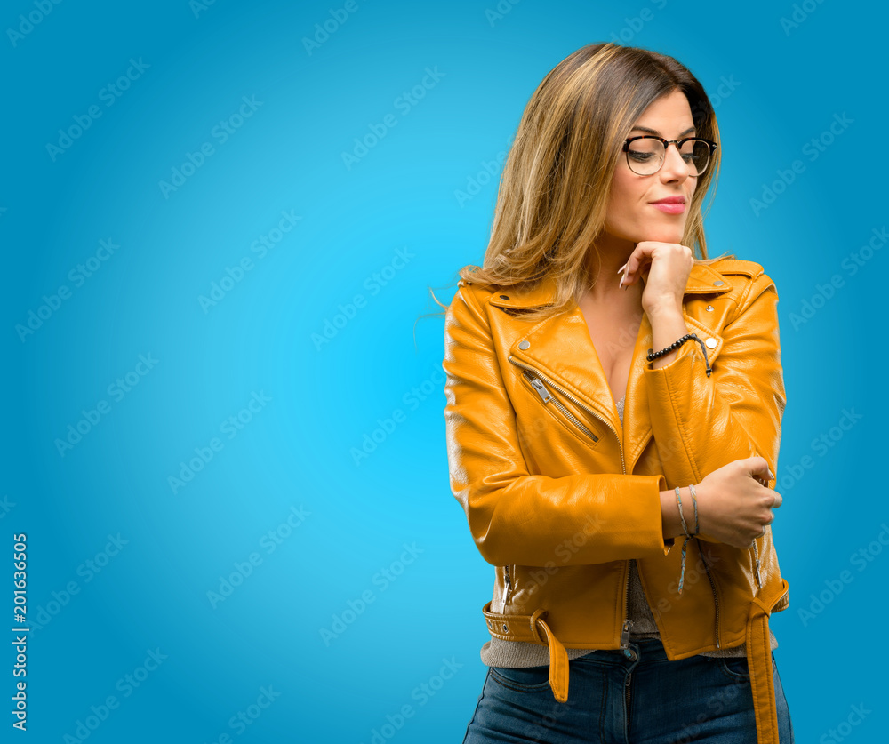 Beautiful young woman thinking thoughtful with smart face, blue background Beautiful young woman thinking thoughtful with smart face, blue background