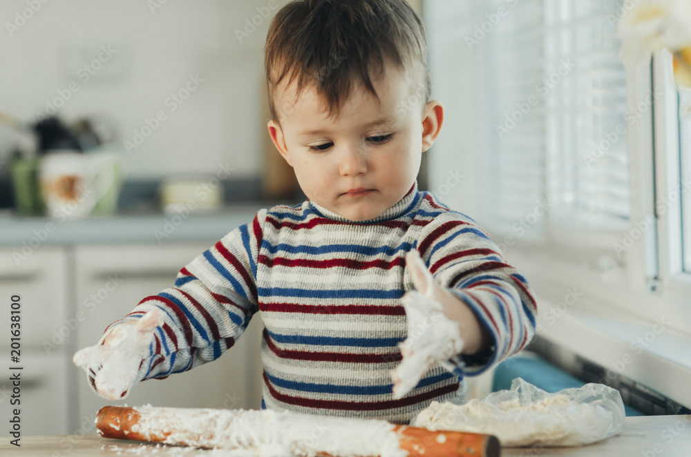 Fototapeta premium the child makes dough from flour house kitchen, played with the little chef