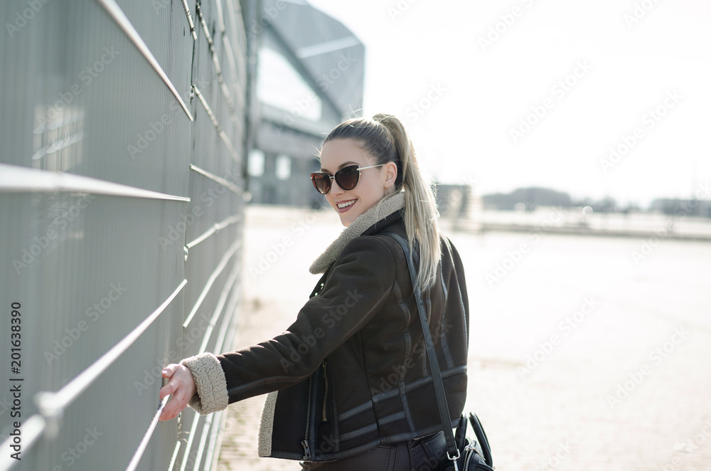 Outdoor portrait of smiling happy woman wearing stylish outfit and walking, sunshine