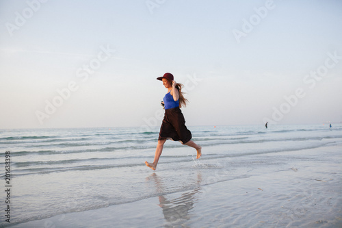 A beautiful girl runs along the shore of the sea against a beautiful sunset