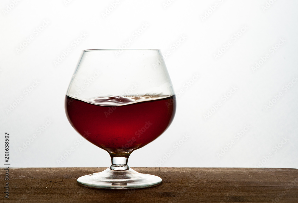 Glass of brandy or cognac on the wooden and white background with copy space Glass of brandy or cognac on the wooden and white background with copy space
