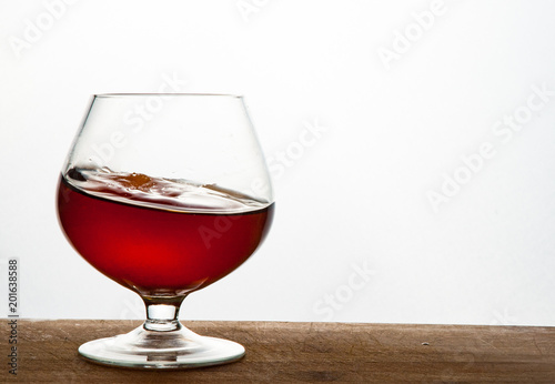 Glass of brandy or cognac on the wooden and white background with copy space