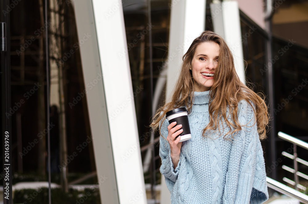 Fototapeta premium Young attractive lady with long curly hair with coffee to go, wearing stylish clothes