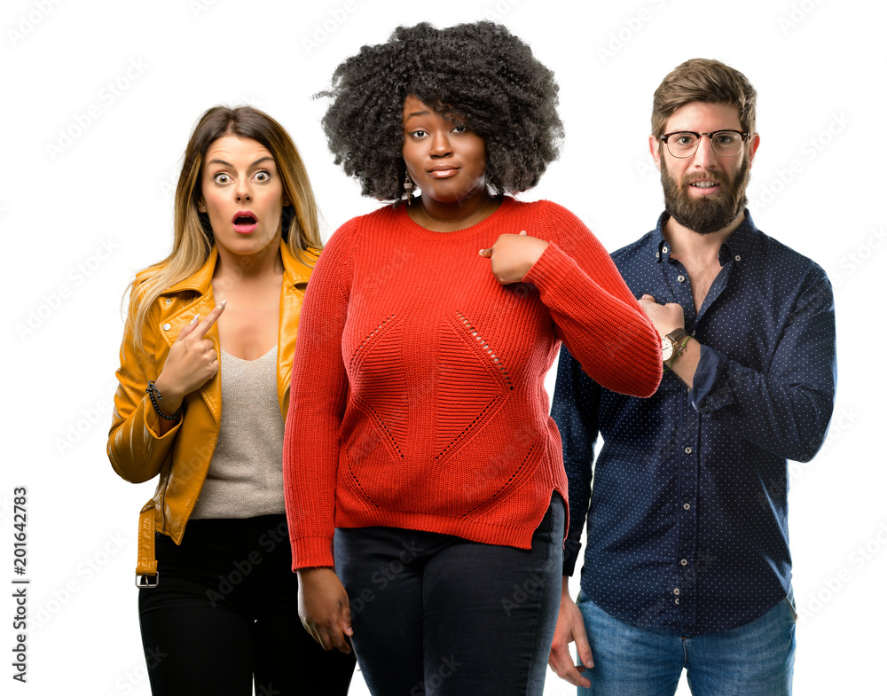 Group of three young men and women happy and surprised cheering expressing wow gesture, pointing with finger Group of three young men and women happy and surprised cheering expressing wow gesture, pointing with finger