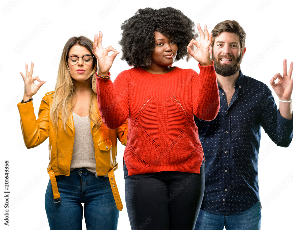 Group of three young men and women doing ok sign gesture with both hands expressing meditation and relaxation Group of three young men and women doing ok sign gesture with both hands expressing meditation and relaxation