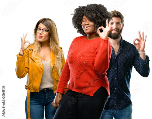 Vászonkép Group of three young men and women doing ok sign with hand, approve gesture