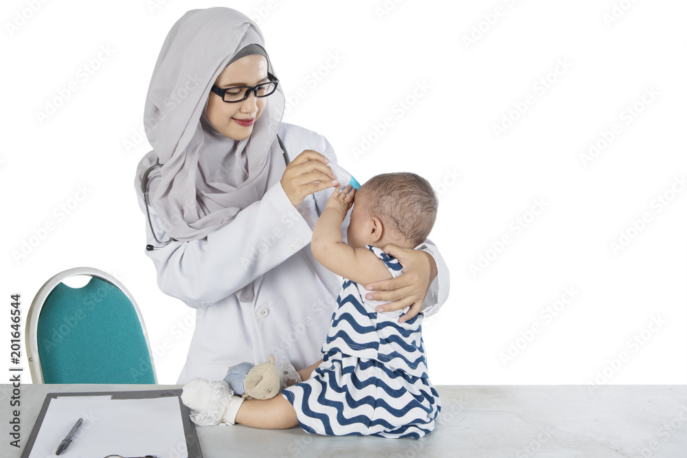Muslim pediatrician examining her patient on studio Muslim pediatrician examining her patient on studio